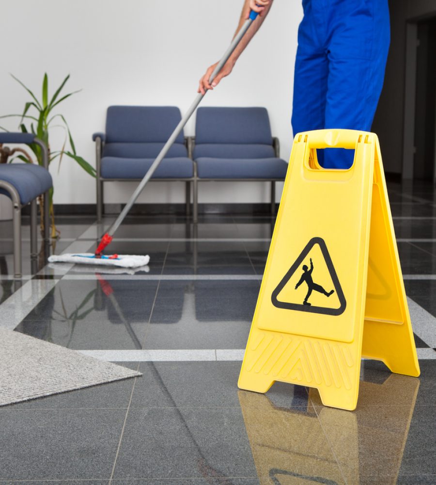 Close-up Of Man Cleaning The Floor With Yellow Wet Floor Sign